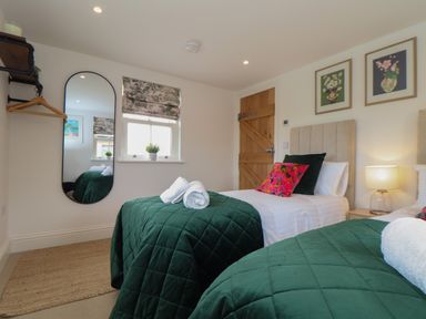 A bedroom with two single beds green quilted bedspreads and rolled towels at Victory View in Pendeen
