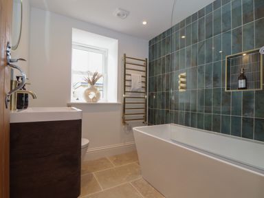 A bathroom with a bathtub a sink a towel rack and a window at Victory View in Pendeen