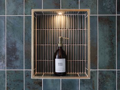 A wall niche with a bottle of body wash and a light above it at Victory View in Pendeen