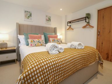 A bedroom with a bed with multiple pillows and rolled towels topped with a checkered blanket at Victory View in Pendeen