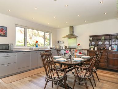 A kitchen with a dining table set with plates and glasses and wooden chairs at Sweden Bridge Cottage in Ambleside