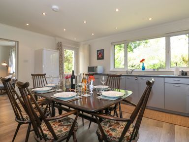 A kitchen with a dining table set with plates glasses and bottles and wooden chairs at Sweden Bridge Cottage in Ambleside