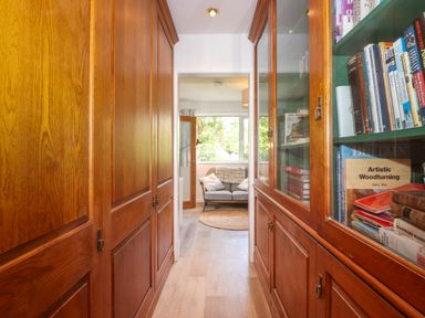 A hallway with wooden cabinets on both sides leading to a room with a sofa and a rug at Sweden Bridge Cottage in Ambleside