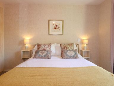 A bedroom with a double bed two bedside tables with lamps and framed art on the wall at Sweden Bridge Cottage in Ambleside