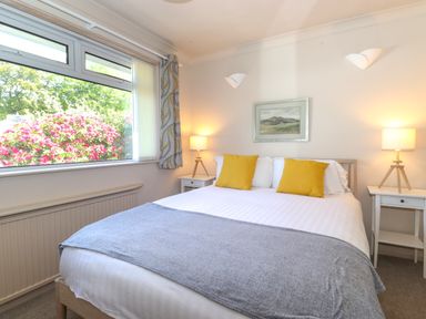 A bedroom with a double bed yellow pillows bedside tables and lamps at Sweden Bridge Cottage in Ambleside