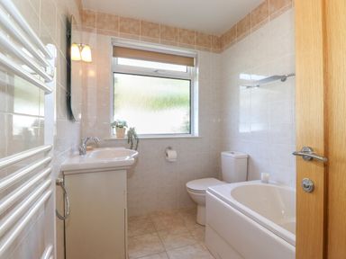 A bathroom with a sink cabinet a toilet a bathtub a window and a towel radiator at Sweden Bridge Cottage Ambleside