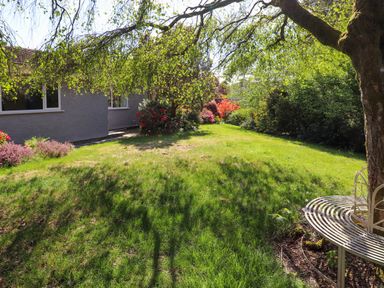 A garden area with grass trees and shrubs near a building at Sweden Bridge Cottage in Ambleside