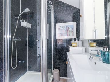 A bathroom with a shower enclosure sink cabinet and a framed picture on the wall at Garibaldi Cottage in Weymouth
