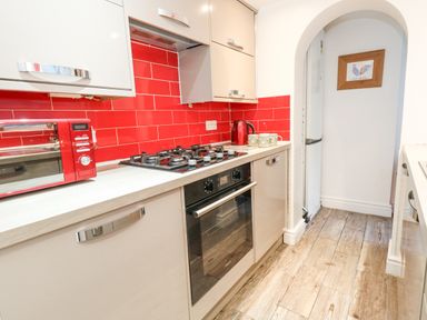 A kitchen with red tiled backsplash and appliances at Garibaldi Cottage in Weymouth
