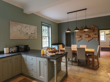 A kitchen and dining area with a table and chairs and kitchen appliances at Llwynderw Hall in Abergwesyn near Llanwrtyd Wells