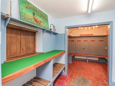 A room with wooden benches a green counter and hooks on walls for hanging items at Llwynderw Hall in Abergwesyn near Llanwrtyd Wells