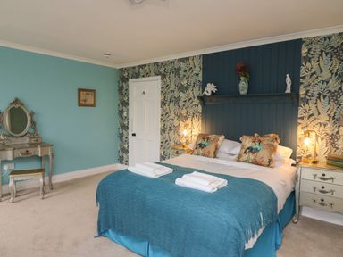 A bedroom with a double bed two bedside tables a dressing table and floral wallpaper at Llwynderw Hall in Abergwesyn near Llanwrtyd Wells