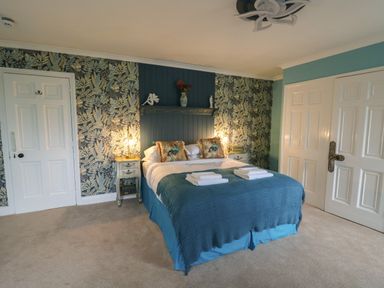 A bedroom with a double bed blue bedding and two bedside tables with lamps at Llwynderw Hall in Abergwesyn near Llanwrtyd Wells
