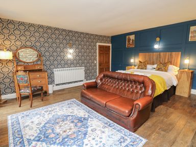 A bedroom with a leather sofa a wooden bed and a dressing table at Llwynderw Hall in Abergwesyn near Llanwrtyd Wells