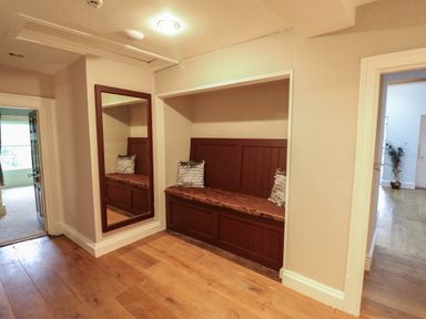 A hallway with wooden floor a built in wooden bench with cushions and a large wall mirror at Llwynderw Hall in Abergwesyn near Llanwrtyd Wells