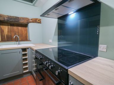 A kitchen with a black stove and oven a wooden countertop and a sink under a wooden window at Llwynderw Hall in Abergwesyn near Llanwrtyd Wells