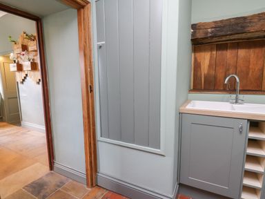 A kitchen area with a sink and wooden framed window next to a doorway and planter boxes on the wall at Llwynderw Hall in Abergwesyn near Llanwrtyd Wells