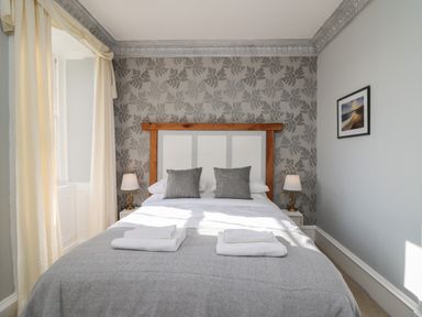 A bedroom with a bed two gray pillows two bedside lamps and folded towels on the bed at Llwynderw Hall in Abergwesyn near Llanwrtyd Wells