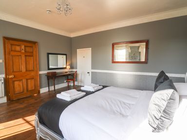 A bedroom with a bed with towels on it a wooden desk and chair and two mirrors on the walls at Llwynderw Hall in Abergwesyn near Llanwrtyd Wells