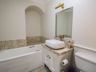 A bathroom with a bathtub sink toilet mirror and tiled countertop at Llwynderw Hall in Abergwesyn near Llanwrtyd Wells
