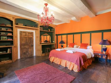 A bedroom with a double bed and bedside tables with lamps and a red chandelier at Llwynderw Hall in Abergwesyn near Llanwrtyd Wells