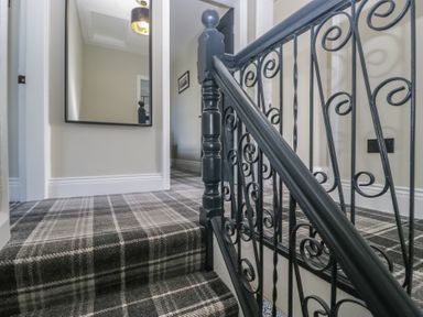 A staircase with a handrail and a mirror in a hallway at 5 Thornbarrow Road