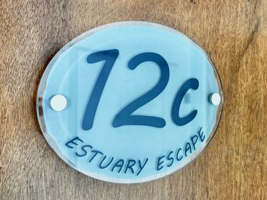A sign with the number 12c and the text Estuary Escape on a wooden surface