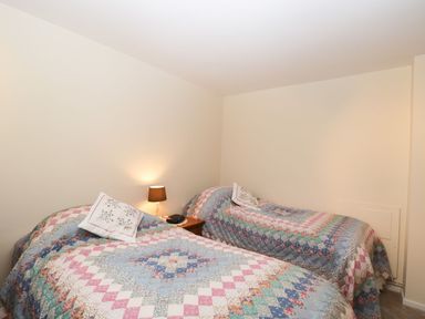 A bedroom with two beds covered in patterned quilts and a bedside table with a lamp and phone at Ground Floor Annex in Milton-Under-Wychwood