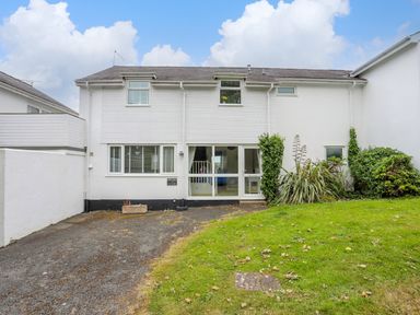 The front exterior of a two story white house with a driveway and lawn at Mor Glas in Abersoch