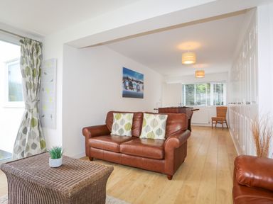 A living room with brown leather sofas a wicker coffee table and a foosball table at Mor Glas in Abersoch