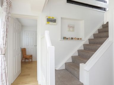 A stairway with carpet and a welcome sign on a wall niche at Mor Glas in Abersoch