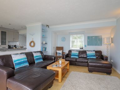 A living room with two brown leather sofas with blue striped cushions a wooden coffee table and a lamp at Mor Glas in Abersoch