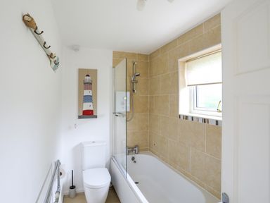 A bathroom with a bathtub shower combination and a toilet at Mor Glas in Abersoch