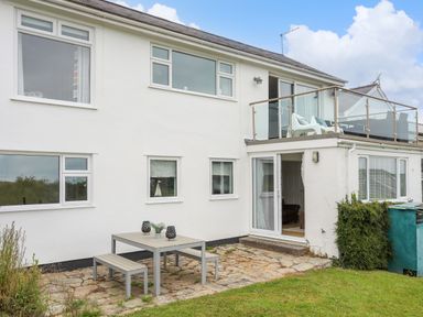 An exterior view of a two-story white house with patio furniture and a balcony at Mor Glas in Abersoch