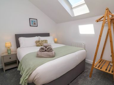 A bedroom with a double bed side tables lamps a wooden clothes rack and a skylight window at Ladybird Rest in Parkham near Bideford