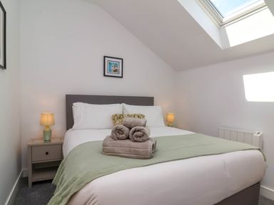 A bedroom with a bed with towels on it bedside tables with lamps and a skylight window at Ladybird Rest in Parkham near Bideford