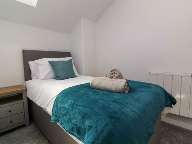 A bedroom with a single bed a bedside table and rolled towels on the bed at Ladybird Rest in Parkham near Bideford