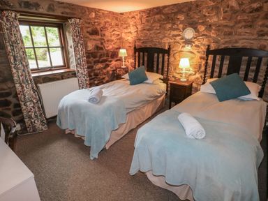 A bedroom with two single beds and stone walls at The Old Stable in Pontfaen near Fishguard