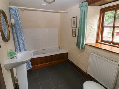 A bathroom with a bathtub sink mirror window radiator and two framed pictures at The Old Stable in Pontfaen near Fishguard