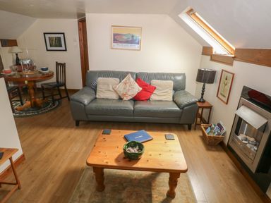 A living room with a gray sofa and cushions wooden coffee table lamp and fireplace at The Loft in Pontfaen near Fishguard