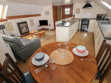 A kitchen and living area with a dining table set for two and a sofa at The Loft in Pontfaen near Fishguard