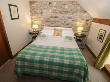 A bedroom with a double bed and green checkered blanket at The Loft in Pontfaen near Fishguard