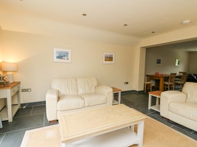 A living room with beige sofas wooden coffee table side tables lamp and wall pictures at Beachway in Brynhenllan near Dinas Cross