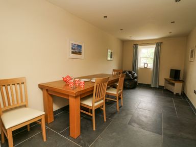 A dining room with a wooden table four chairs red polka dot tea set a bean bag chair and a television at Beachway in Brynhenllan near Dinas Cross