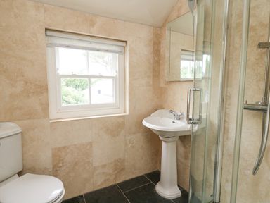 A bathroom with a toilet a pedestal sink a glass shower enclosure and a window at Beachway in Brynhenllan near Dinas Cross