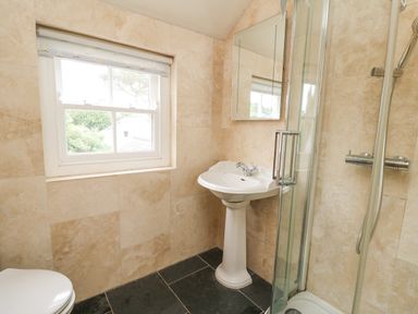 A bathroom with a window pedestal sink mirror shower and toilet at Beachway in Brynhenllan near Dinas Cross