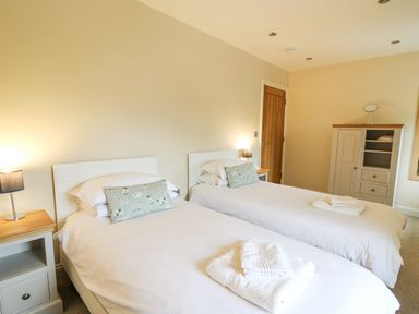 A bedroom with two single beds bedside tables lamps and a wardrobe at Beachway in Brynhenllan near Dinas Cross