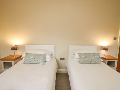 A bedroom with two single beds with white headboards and animal print cushions at Beachway in Brynhenllan near Dinas Cross