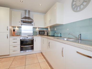A kitchen with cabinets, sink, and stove at Blissful Ocean Breeze in Perranporth