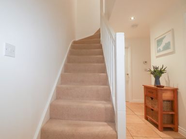 A hallway with stairs and a table at Blissful Ocean Breeze in Perranporth